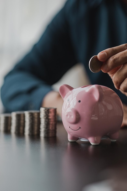 Un homme d'affaires tenant une pièce de monnaie dans une tirelire Placer des pièces de monnaie dans une rangée de bas en haut est comparable à économiser de l'argent pour croître davantage Le concept de croissance de l'épargne et d'épargne en investissant dans des fonds d'actions