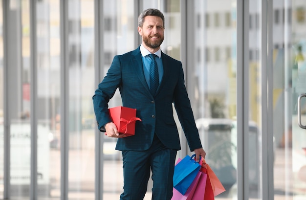 Homme d'affaires tenant des sacs d'achat et marchant dans le magasin d'achat achetant et payant shopaholic