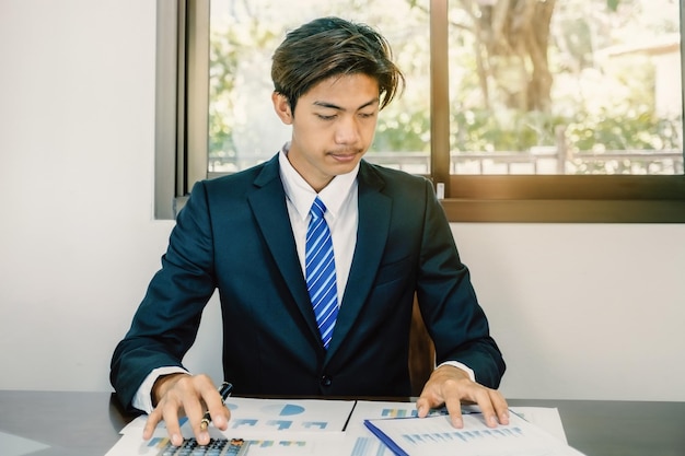 Homme d'affaires tenant un stylo analyse le graphique avec un ordinateur portable au bureau à domicile