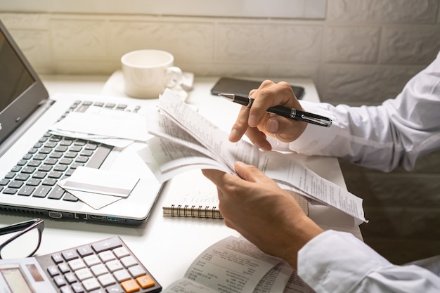 Un homme d'affaires tenant un stylo tout en regardant les factures sur son lieu de travail. Concept d'entreprise.