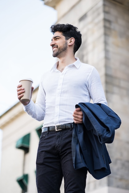 Homme d'affaires tenant une tasse de café sur le chemin du travail à l'extérieur