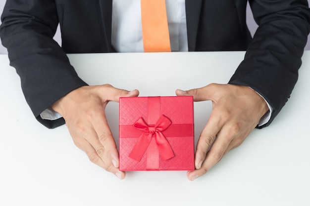 Homme d&#39;affaires tend la boîte cadeau rouge