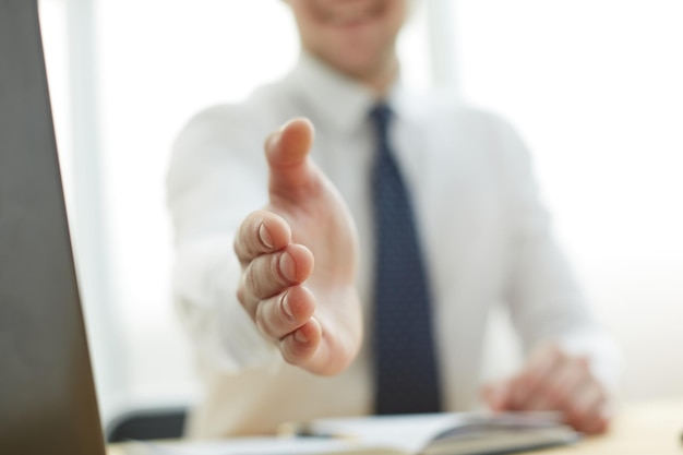 Homme d'affaires tendant la main pour serrer au bureau