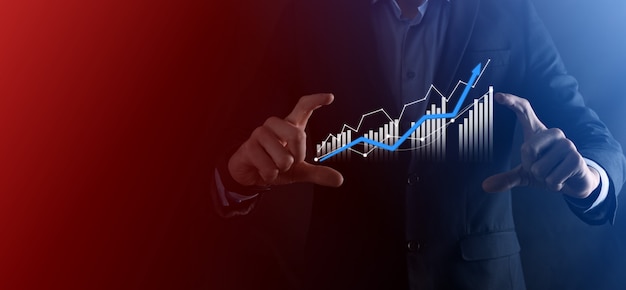 L'homme d'affaires tient le dessin sur le graphique croissant de l'écran, la flèche de l'icône de croissance positive.