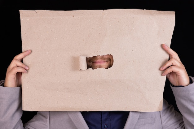 Un homme d'affaires tient une feuille de papier avec un trou pour sa bouche. Concept de censure. Concept d'entreprise.