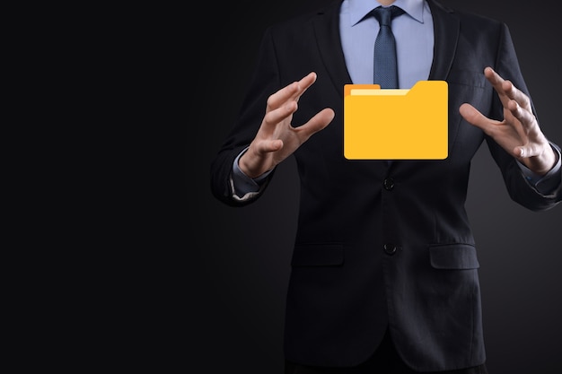L'homme d'affaires tient l'icône du dossier.Le système de gestion de documents ou la configuration DMS par un consultant informatique avec un ordinateur moderne recherche des informations de gestion et des fichiers d'entreprise.Traitement d'entreprise,