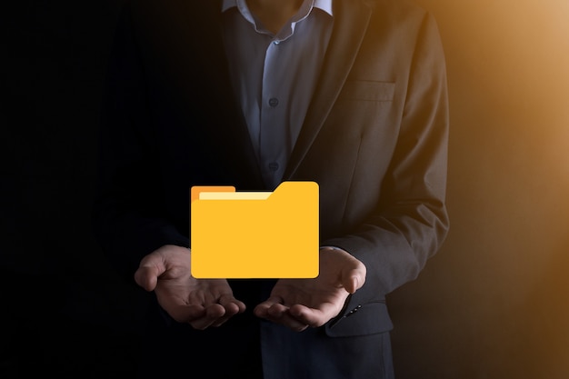 L'homme d'affaires tient l'icône du dossier.Le système de gestion de documents ou la configuration DMS par un consultant informatique avec un ordinateur moderne recherche des informations de gestion et des fichiers d'entreprise.Traitement d'entreprise,