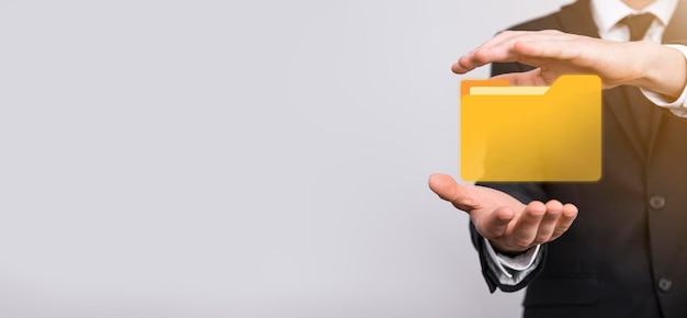 L'homme d'affaires tient l'icône du dossier.Le système de gestion de documents ou la configuration DMS par un consultant informatique avec un ordinateur moderne recherche des informations de gestion et des fichiers d'entreprise.Traitement d'entreprise,