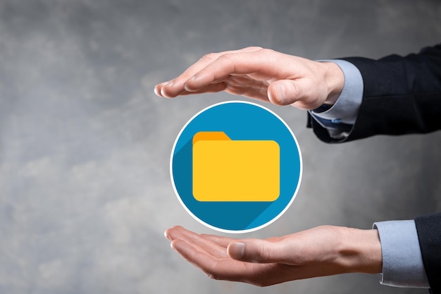 L'homme d'affaires tient l'icône du dossier.Le système de gestion de documents ou la configuration DMS par un consultant informatique avec un ordinateur moderne recherche des informations de gestion et des fichiers d'entreprise.Traitement d'entreprise,