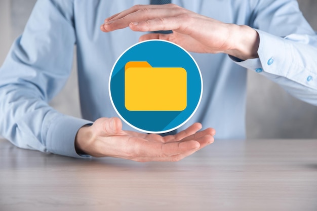 L'homme d'affaires tient l'icône du dossier.Le système de gestion de documents ou la configuration DMS par un consultant informatique avec un ordinateur moderne recherche des informations de gestion et des fichiers d'entreprise.Traitement d'entreprise,