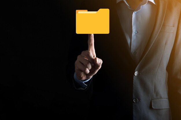L'homme d'affaires tient l'icône du dossier.Le système de gestion de documents ou la configuration DMS par un consultant informatique avec un ordinateur moderne recherche des informations de gestion et des fichiers d'entreprise.Traitement d'entreprise,