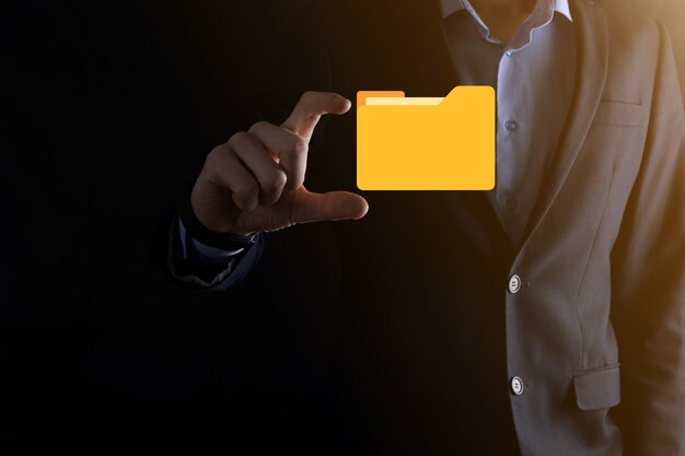 L'homme d'affaires tient l'icône du dossier.Le système de gestion de documents ou la configuration DMS par un consultant informatique avec un ordinateur moderne recherche des informations de gestion et des fichiers d'entreprise.Traitement d'entreprise,