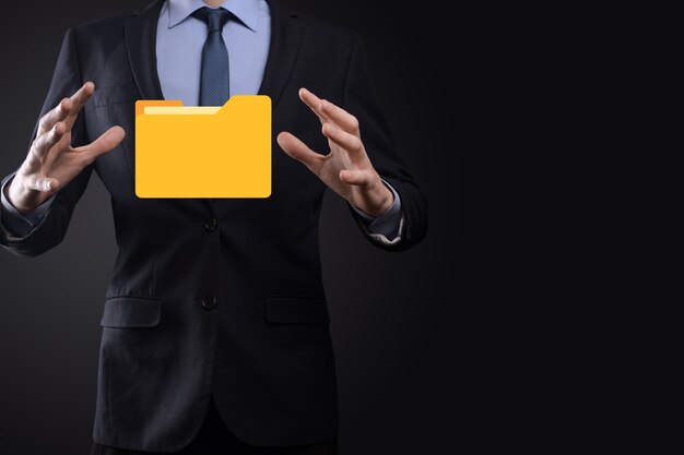L'homme d'affaires tient l'icône du dossier.Le système de gestion de documents ou la configuration DMS par un consultant informatique avec un ordinateur moderne recherche des informations de gestion et des fichiers d'entreprise.Traitement d'entreprise,