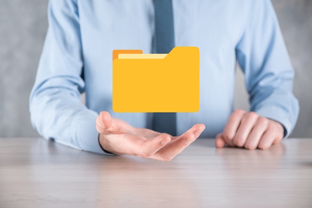 L'homme d'affaires tient l'icône du dossier.Le système de gestion de documents ou la configuration DMS par un consultant informatique avec un ordinateur moderne recherche des informations de gestion et des fichiers d'entreprise.Traitement d'entreprise,
