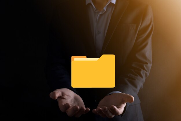 L'homme d'affaires tient l'icône du dossier.Le système de gestion de documents ou la configuration DMS par un consultant informatique avec un ordinateur moderne recherche des informations de gestion et des fichiers d'entreprise.Traitement d'entreprise,
