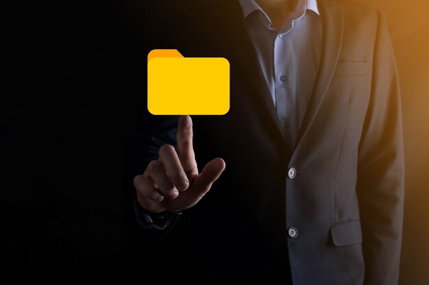 L'homme d'affaires tient l'icône du dossier.Le système de gestion de documents ou la configuration DMS par un consultant informatique avec un ordinateur moderne recherche des informations de gestion et des fichiers d'entreprise.Traitement d'entreprise,