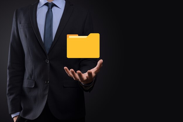 L'homme d'affaires tient l'icône du dossier.Le système de gestion de documents ou la configuration DMS par un consultant informatique avec un ordinateur moderne recherche des informations de gestion et des fichiers d'entreprise.Traitement d'entreprise,