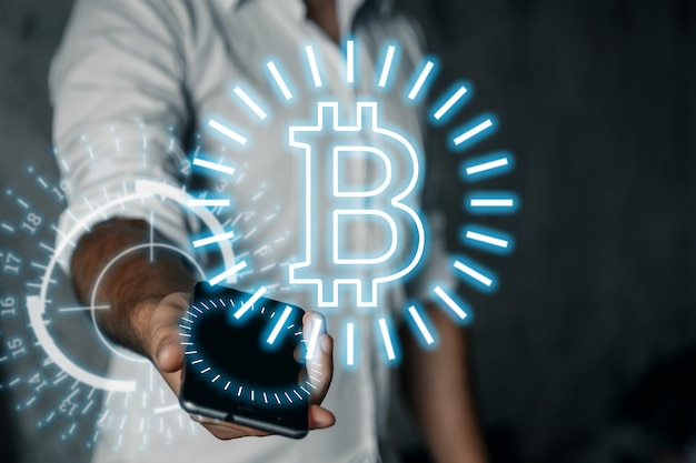 Un homme d'affaires tient un téléphone, une icône de bitcoin, une entreprise, de nouvelles technologies à la main.