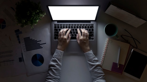 Homme d'affaires travaillant au bureau avec analyse financière. Vue de dessus du lieu de travail de bureau avec l'homme à l'aide d'un ordinateur portable avec un écran vide à table dans le bureau.