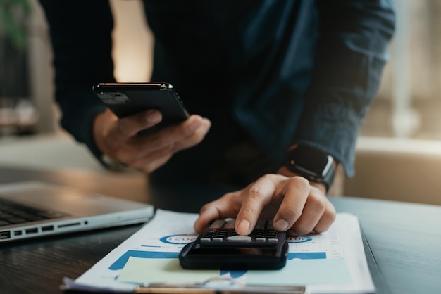 Homme d'affaires travaillant sur un bureau avec une calculatrice pour calculer