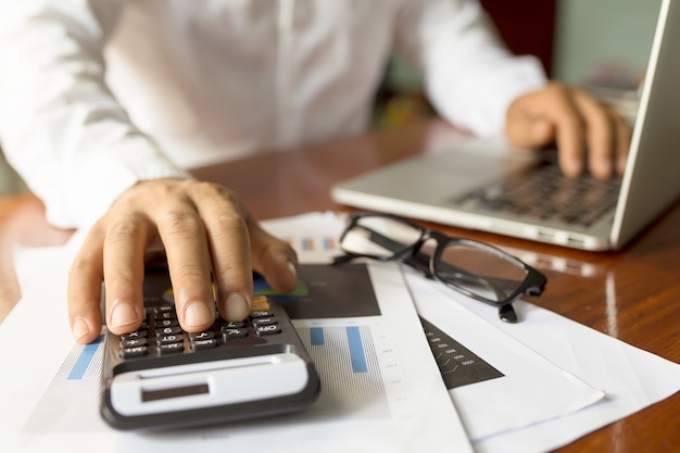 Photo homme d'affaires travaillant avec un lieu de travail moderne avec un ordinateur portable sur une table en bois, main de l'homme sur un clavier d'ordinateur portable pour le travail à domicile,