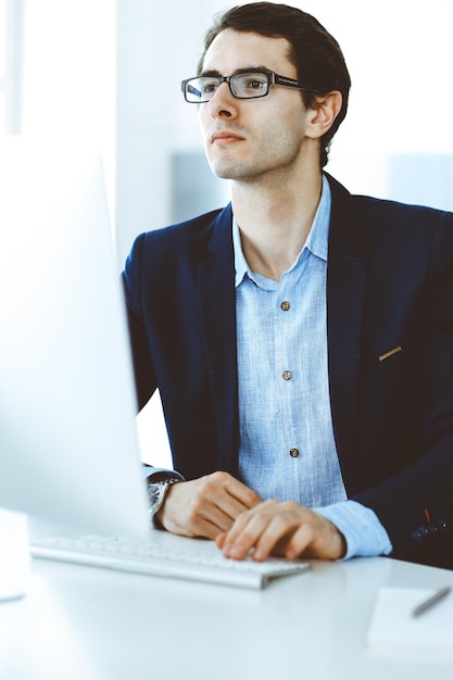 Homme d'affaires travaillant avec un ordinateur dans un bureau moderne. Tête d'un entrepreneur masculin ou d'un chef d'entreprise sur le lieu de travail. Notion d'entreprise.