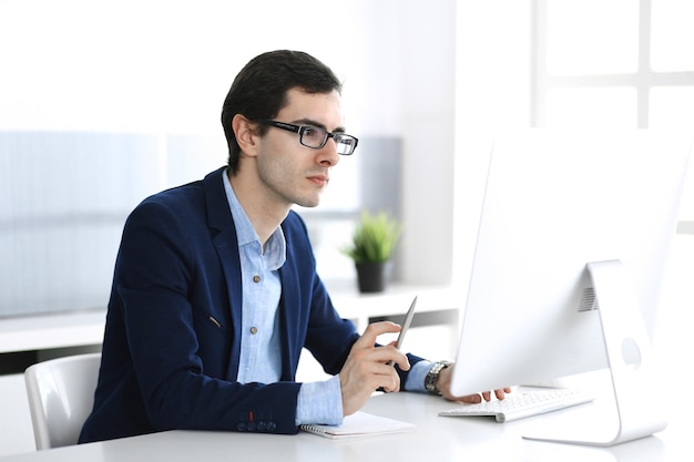 Homme d'affaires travaillant avec un ordinateur dans un bureau moderne. Tête d'un entrepreneur masculin ou d'un chef d'entreprise sur le lieu de travail. Notion d'entreprise.