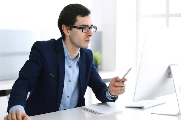 Homme d'affaires travaillant avec un ordinateur dans un bureau moderne. Tête d'un entrepreneur masculin ou d'un chef d'entreprise sur le lieu de travail. Notion d'entreprise.
