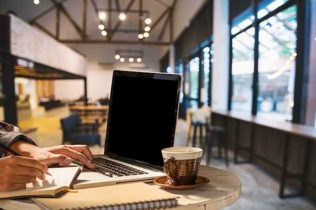 Homme d&#39;affaires travaillant avec ordinateur portable avec écran blanc et café dans un café comme le ba