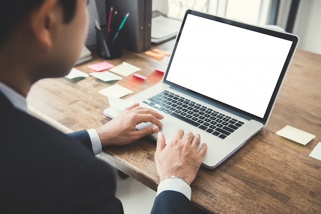 Homme d'affaires travaillant sur un ordinateur portable avec un écran blanc vide à son bureau