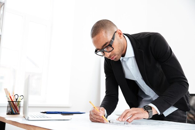 Homme d'affaires travaillant en regardant les statistiques dans un document papier debout au bureau au bureau