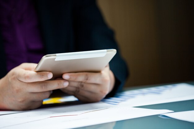 Homme d&#39;affaires travaillant sur tablette numérique avec document de données graphique sur le bureau