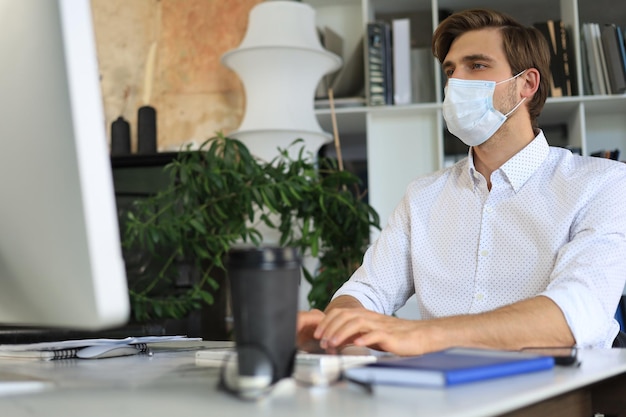 L'homme d'affaires travaille dans un masque médical préventif au bureau.