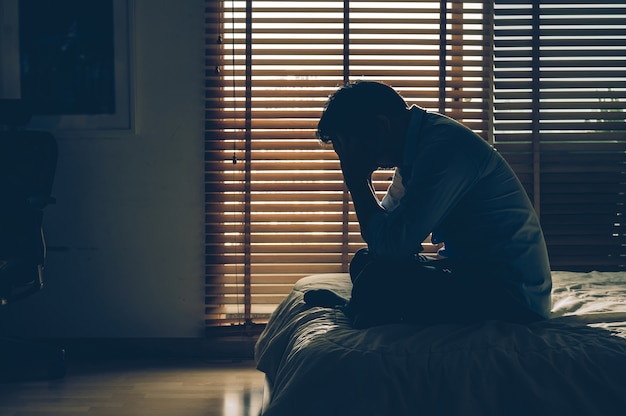 Homme D'affaires Triste Assis Tête Dans Les Mains Sur Le Lit Dans La Chambre Sombre