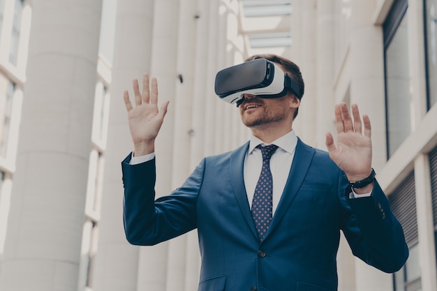 Homme d'affaires utilisant un casque VR pour un jeu de réalité virtuelle pour le travail, debout à l'extérieur