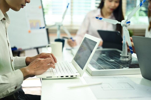 Photo homme d'affaires utilisant un ordinateur portable alors qu'il travaille sur un projet d'innovation durable avec une équipe au bureau