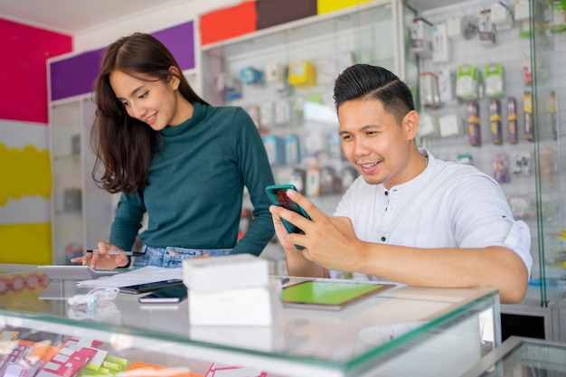 Un homme d'affaires utilisant un smartphone et une femme d'affaires utilisant une calculatrice