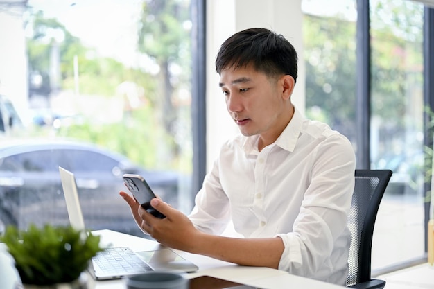 Un homme d'affaires utilisant son smartphone assis à son bureau au bureau