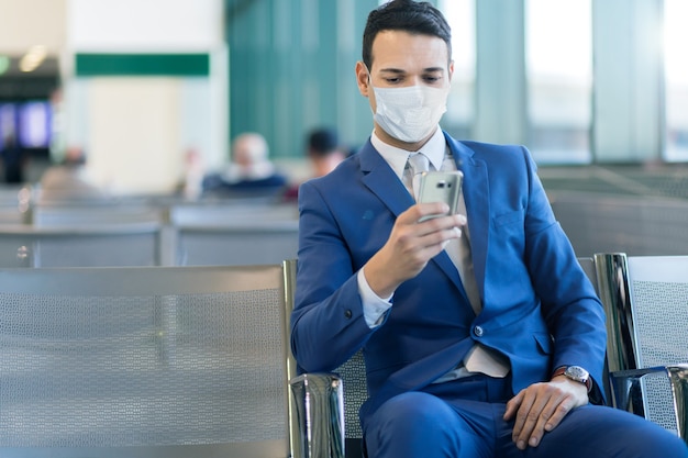 Homme d'affaires utilisant le téléphone à l'aéroport, concept de covid ou de coronavirus