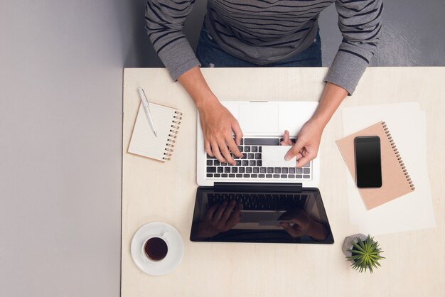 L'homme d'affaires utilise une carte et tape sur un ordinateur portable à la table de bureau. Vue de dessus