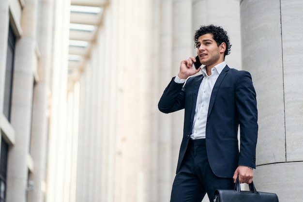 Un homme d'affaires utilise un téléphone dans un costume formel pour aller travailler au bureau