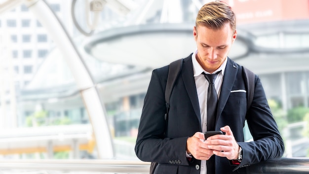 Homme d'affaires utilise un téléphone intelligent dans une suite de tissu intelligent à la ville en plein air.