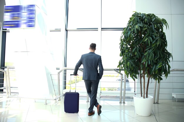 Homme d'affaires avec valise dans le hall de l'aéroport.