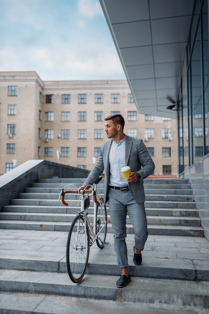 Homme d'affaires avec vélo descend les escaliers