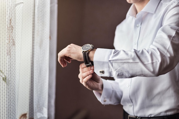 Homme d'affaires vérifiant l'heure sur sa montre-bracelet homme mettant l'horloge sur le marié se préparant le matin avant la cérémonie de mariage