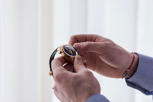 Homme d'affaires vérifiant l'heure sur sa montre-bracelet homme mettant l'horloge sur le marié se préparant le matin avant la cérémonie de mariage