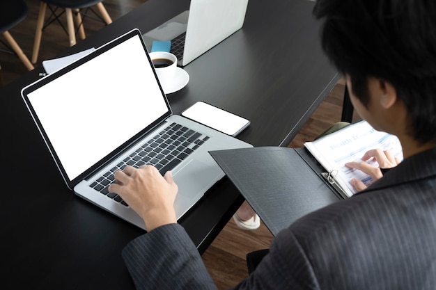 Homme d'affaires vérifiant le rapport et travaillant avec un ordinateur portable