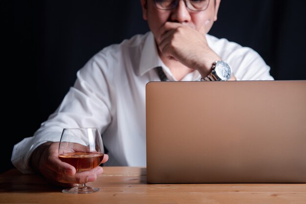 Un homme d'affaires avec un verre de whisky à cause du stress de travailler dur la nuit