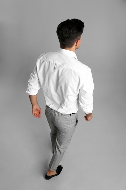 Homme d'affaires en vêtements formels sur fond gris vue arrière