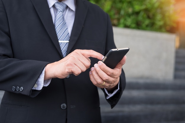 Homme D'affaires Vêtu D'un Costume Noir Et Utilisant Un Smartphone Moderne En Plein Air